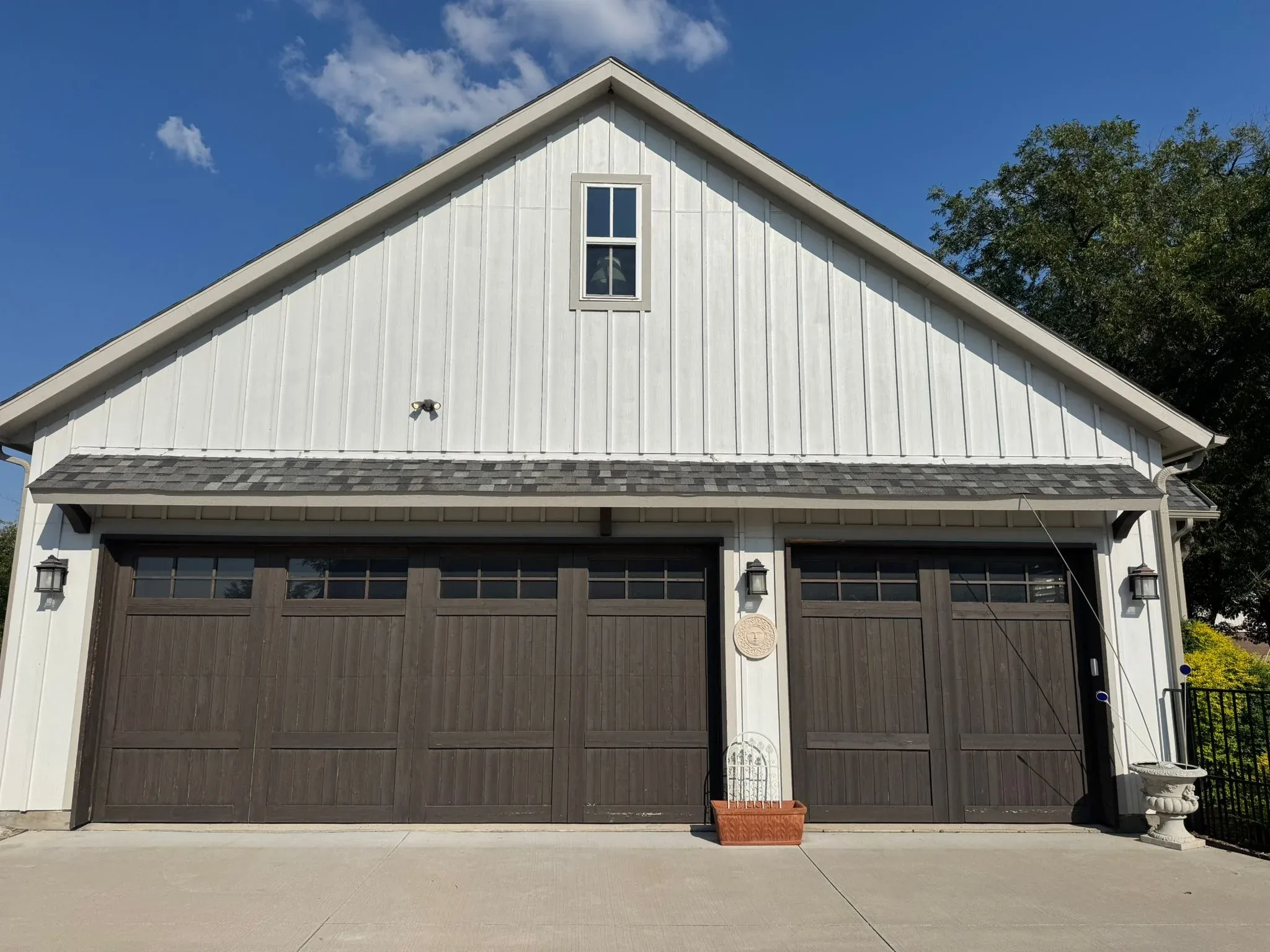 A carriage-style double garage door in dark wood tones on a white board-and-batten garage