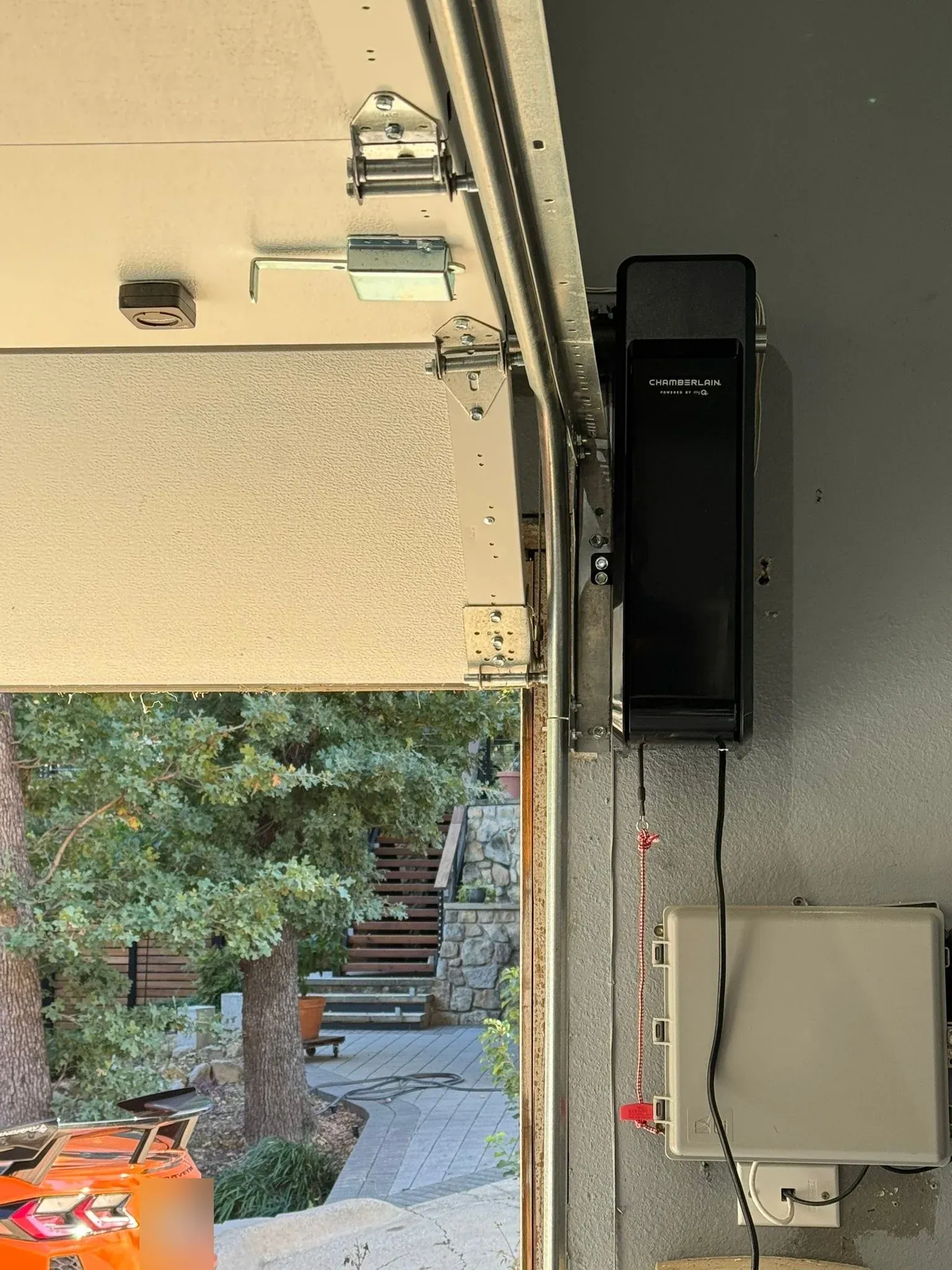 A Chamberlain wall-mount opener fixed beside the door track, the raised door opening onto a wooded patio